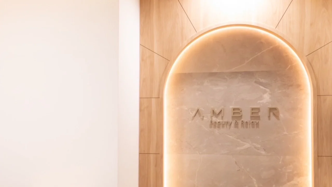 木目の壁にアーチ型の間接照明が灯る、AMBER -Beauty&Relax-のエントランス